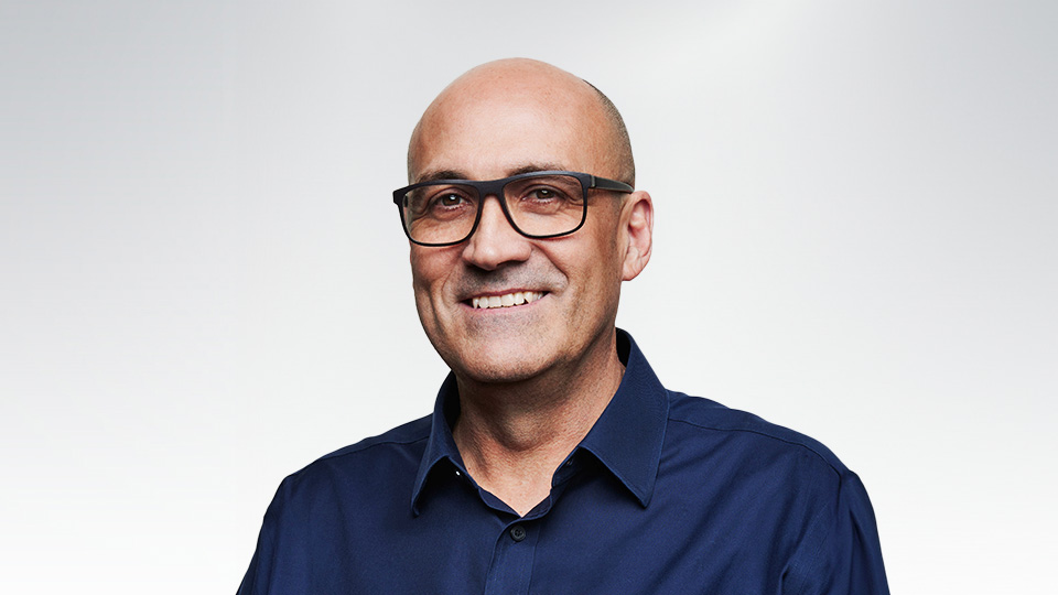 Bald smiling man wearing glasses.